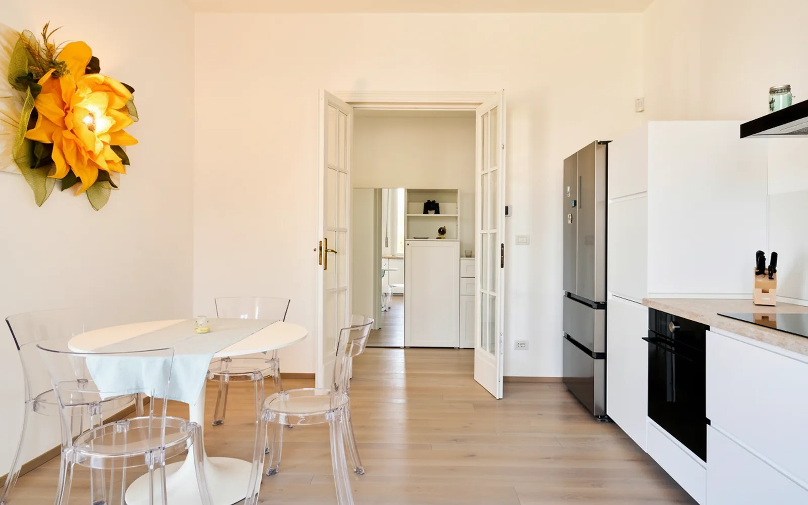 Zona pranzo con tavolo rotondo e cucina con frigorifero americano