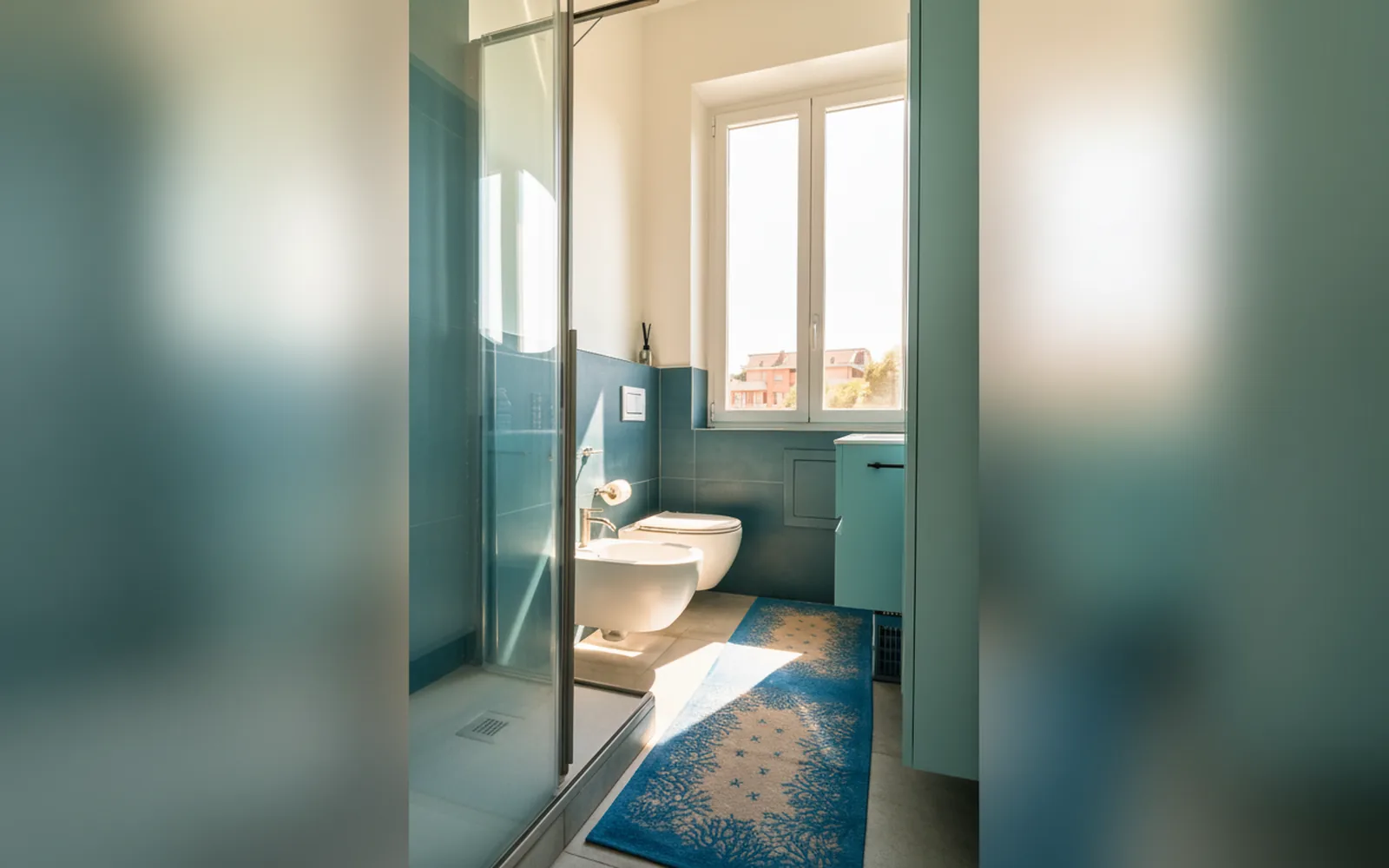 Bagno con doccia in vetro e piastrelle verde acqua